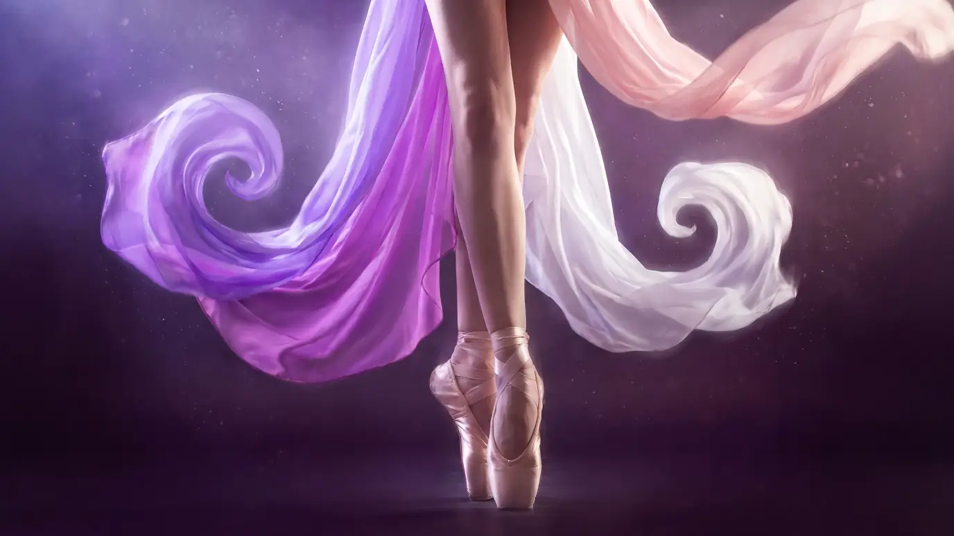 Close-up of a ballerina's legs en pointe in pale pink satin pointe shoes, with ribbons of blush, violet and white silk swirling through the air around her.